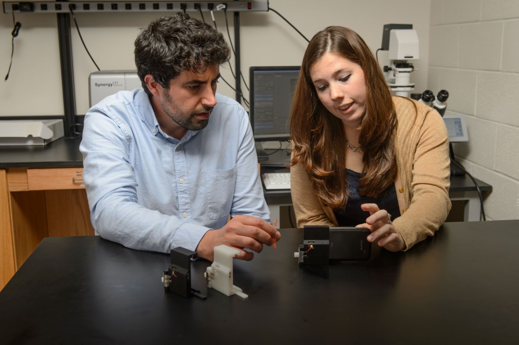 Graduate student Stephanie Knowlton, right, and Savas Tasoglu, assistant professor of mechanical engineering, with a device to analyze blood for sickle cell disease. (Peter Morenus/UConn Photo)
