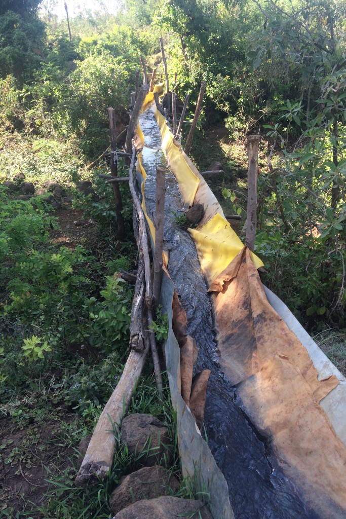 A makeshift aqueduct, constructed by the villagers using plastic tarps, sheet metal and sticks. The inventive structure has a large hole in the underside, which results in substantial water loss.