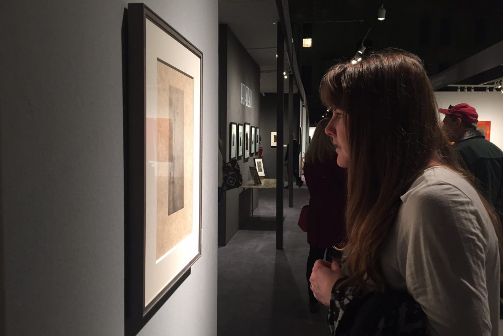 MFA candidate Kelsey Miller examines a print at the Independent Art Fair on Varick Street in New York. (Photo courtesy of students in ART 5310 Graduate Seminar)