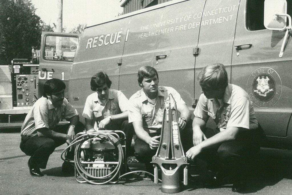 The first UConn Health firefighter paramedics demonstrate a Hurst tool, also known as "the jaws of life." From left: Jerry Rio, Don Perrault, Dave Smith, and Walt Rasmussen. "We had the first one in the Farmington Valley; only Wethersfield and Enfield had one at the time," says Smith, who was an extrication instructor for the state. It weighed about 45 pounds, plus at least another 60 pounds for the motor. (Photo provided by Dave Smith)