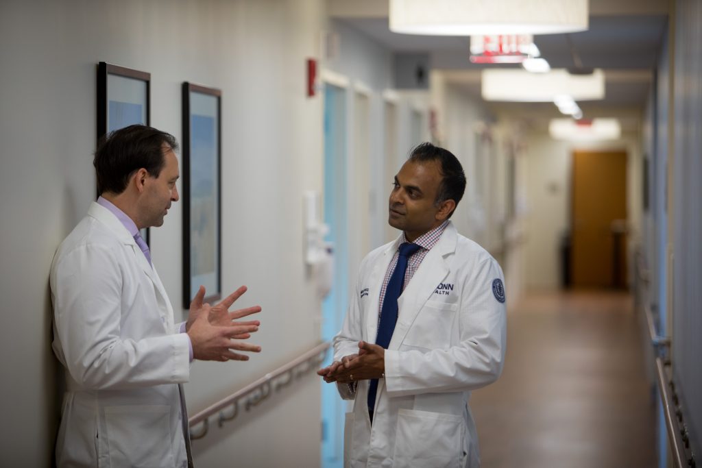 Dr. Alex Merkulov, left, head of women’s imaging at UConn Health, speaks with Dr. Amish Patel, the first graduate of the breast imaging fellowship at the UConn School of Medicine, in the hallway of the Women's Center Imaging Suite at UConn Health. (Paul Horton for UConn)
