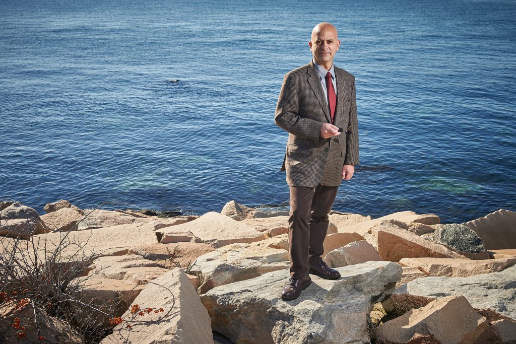 Kroum Batchvarov, an assistant professor in the Department of Anthropology who specializes in nautical archaeology, stands on the rocks beside Long Island Sound at the Avery Point campus. (Peter Morenus/UConn Photo)