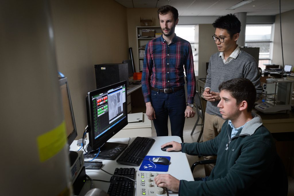 Seok-Woo Lee, assistant professor of materials science and engineering, center, with graduate students Keith Dusoe, left, and John Sypek at the controls of a scanning electron microscope at their lab at the Gant Complex on Oct. 27, 2016. (Peter Morenus/UConn Photo)