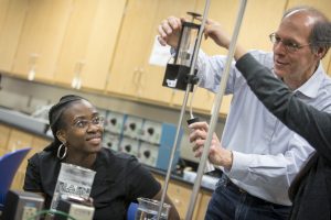 A physics professor helping students whit a physics experiment on Dec. 1, 2016. (Sean Flynn/UConn Photo)