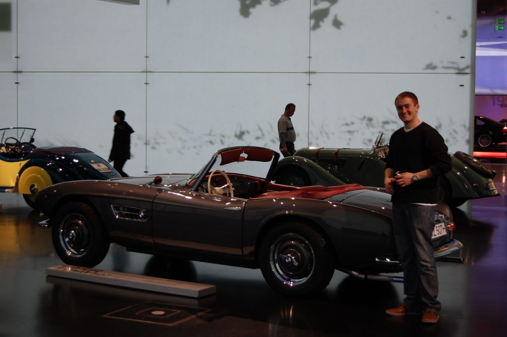 Karl Music, a graduate of the Eurotech program who currently works at Boehringer Ingelheim in Ridgefield, Connecticut, poses next to a car at the BMW Museum in Munich.