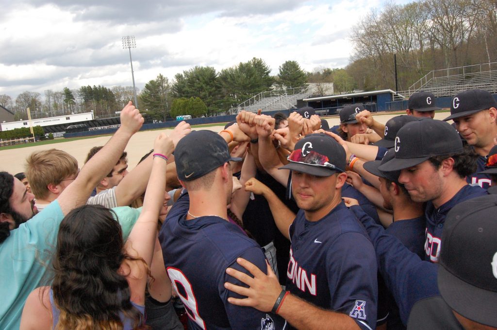 Music students who met with the baseball team as part of the Arts and Athletics program in the School of Fine Arts huddled together on the field after the Huskies’ win over Cincinnati on April 30. (Kenneth Best/UConn Photo)