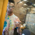 A student writes equations on a glass writing board in the Homer Babbidge Library in May 2017. (Sean Flynn/UConn Photo)