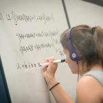 A student writes equations on a glass writing board in the Homer Babbidge Library in May 2017. (Sean Flynn/UConn Photo)