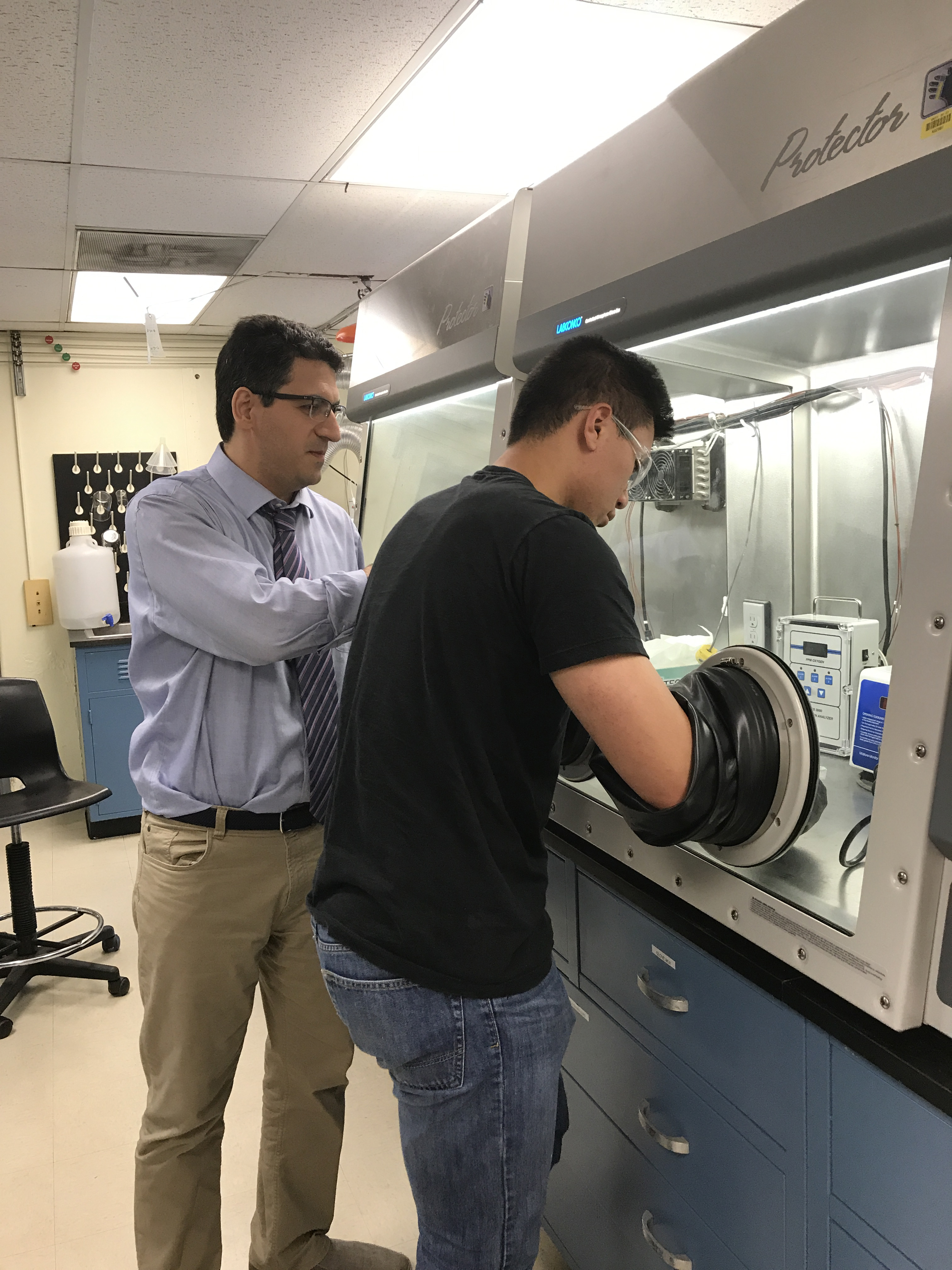 Postdoctoral researcher Peiman Shahbegi and an undergraduate student in materials science work with a glove box to produce nanomaterials.