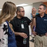 Carrie Vopelak, senior monitoring and evaluation officer for International Medical Corps (left), and volunteer Dr. Rob Fuller, chair and professor of the Department of Emergency Medicine at UConn Health (right), discuss the state of the hospital’s ER with Dr. Robles after Hurricane Maria. (Photo by Ken Cedeno, IMC)
