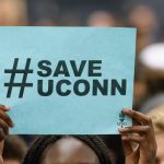 A student holds up a #SaveUConn sign during a rally at the Hugh S. Greer Field House in support of the University on Sept. 20, 2017. (Peter Morenus/UConn Photo)
