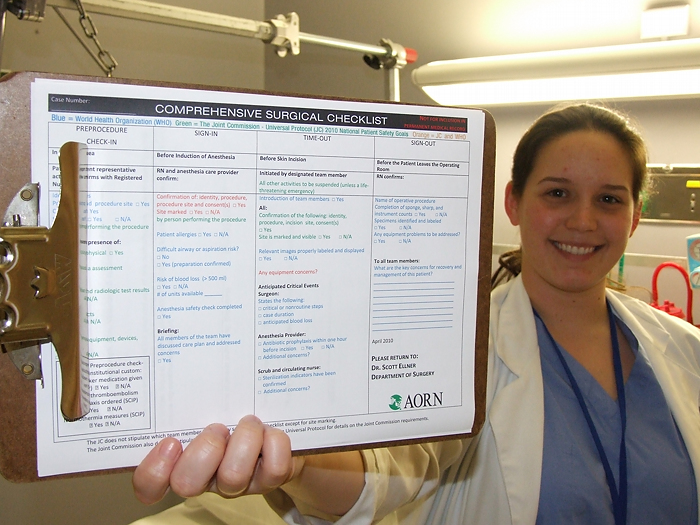 Dr. Lindsay Bliss is holding up a checklist that she designed to improve the culture of the operating room.