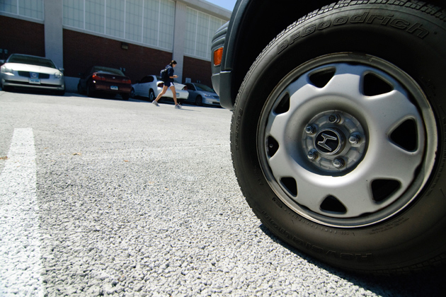 Photo showing the front wheel of a vehicle in a parking lot.