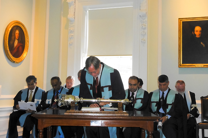 Dr. Douglas Peterson signs the membership roster of the Royal College of Surgeons of Edinburgh, Scotland, before accepting the honor of Fellowship in Dental Surgery Without Examination. (Photo provided by Dr. Matthew Peterson)