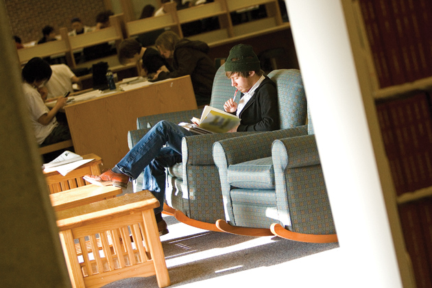 A student with a winter hat reads a book at the Homer Babbidge Library.