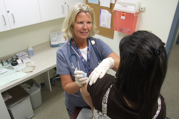 UConn Health Center nurse Marlene Divinere administers a flu shot.
