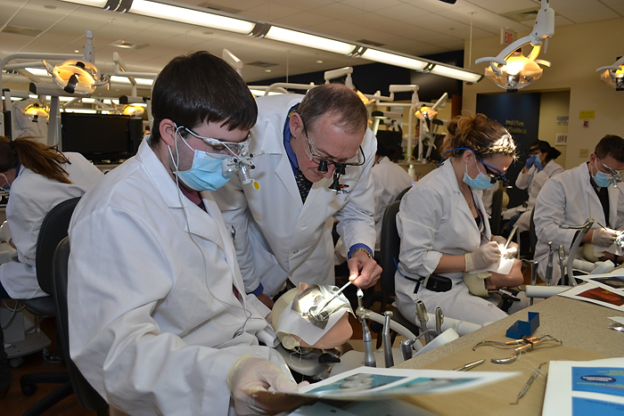 Dr. Jonathan Meiers (second from left), professor and chair of the Division of Operative Dentistry, assists second-year dental student John Walsh. (Tina Encarnacion/UConn Health Center Photo)