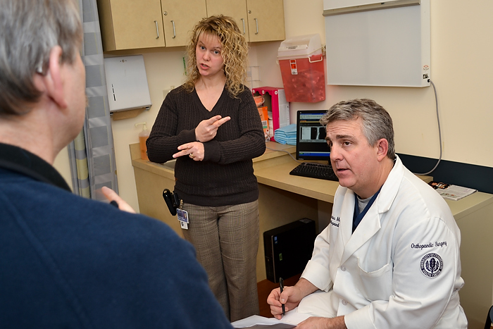 Maranda Reynolds works alongside Dr. Augustus Mazzocca within full visual contact to a deaf patient, insuring uninterrupted medical communication access between doctor and patient on February 24, 2012. (Tina Encarnacion/UConn Health Center Photo)