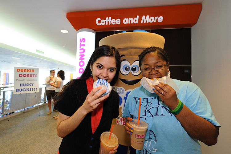 Momina Afrede '14 (CLAS) and Ashly Stovall '14 (CANR), right, each enjoy one of the 1500 blue and white Dunkin Donuts that were given away to celebrate the opening of their new location at the Student Union on March 22, 2012. (Peter Morenus/UConn Photo)