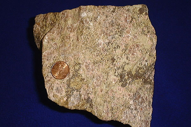 Rare earth ore, shown with a United States penny for size comparison. (Wikipedia)