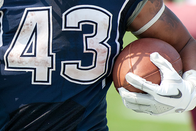 Close-up of a UConn football player holding the ball.