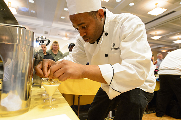 Sterling Townes of South Marketplace puts the finishing touches on part of his team's entry during the Boiling Point competition of the 13th annual Culinary Olympics held at Rome Ballroom on Jan. 17, 2013. (Peter Morenus/UConn Photo)