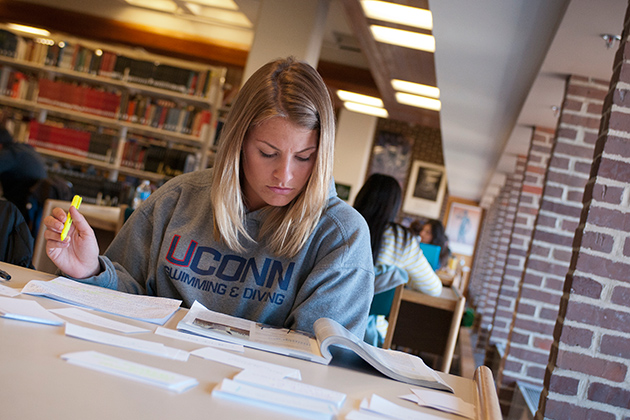 Female student wearing a UConn sweatshirt, studying at a table in the Cue Building (Center for Undergraduate Education) on March 27, 2012. (Al Ferreira for UConn)