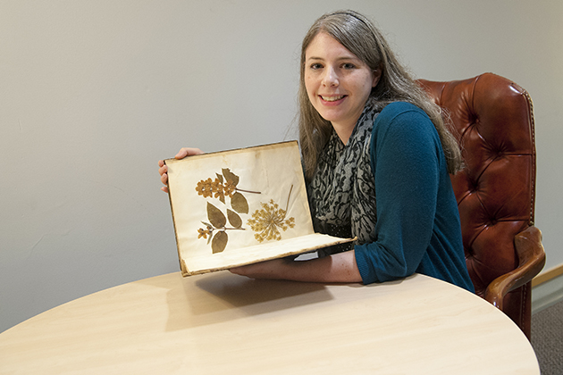 Jessica Linker, a graduate student fellow at the Humanities Institute, with a woman's herbarium from the 1850s. Linker is studying female scientists in the 18th and 19th centuries. (Sean Flynn/UConn Photo)