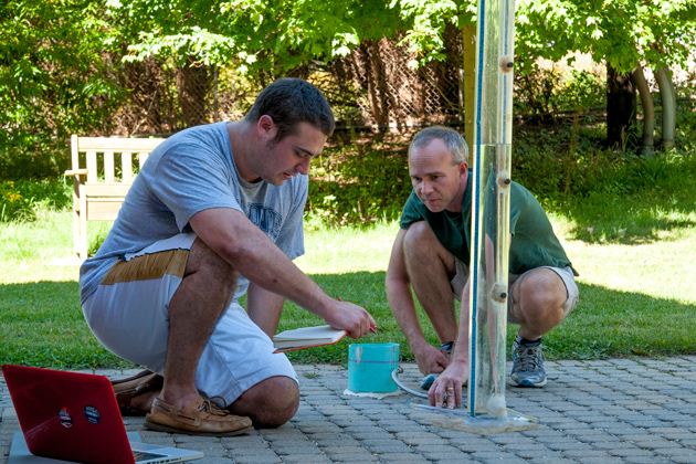 Michael Dietz, assistant Cooperative Extension educator-in-residence, right, and environmental science major Alexander Barresi ’14 (CANR) record the surface infiltration rate of pervious pavement outside the Lakeside Building on North Eagleville Road. (Sean Flynn/UConn Photo)