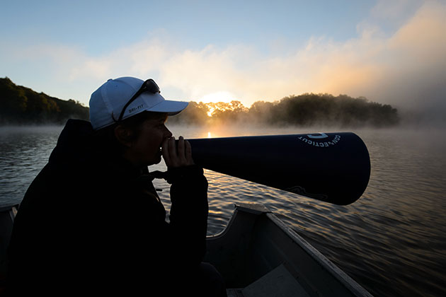 Head Coach Jennifer Sanford-Wendry uses a megaphone to give directions to UConn Rowing team members on Coventry Lake on Sept. 18, 2013. (Peter Morenus/UConn Photo)
