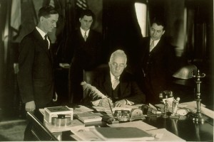 Gov. Wilbur Cross, center, signs the bill that made Connecticut Agricultural College the Connecticut State College in 1933.