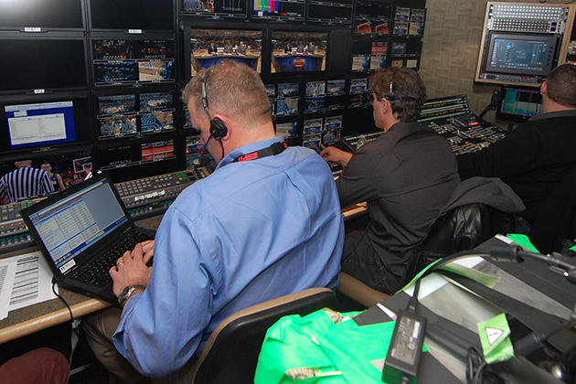 The wall of 54 monitors in the ESPN GameDay production truck, with Doug Holmes, the director, in the blue shirt. (Ken Best/UConn Photo)