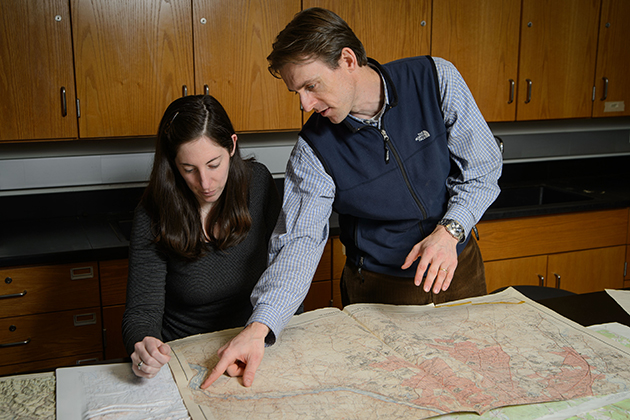 Will Ouimet, assistant professor of geography, and Katharine Johnson, a PhD. student, look over old maps of New England. (Peter Morenus/UConn Photo)