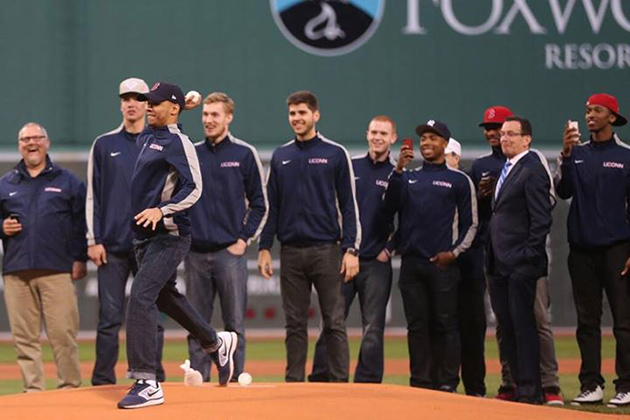 Basketball standout Shabazz Napier '14 (CLAS) throws out the first pitch at Fenway Park in Boston April 22, watched by Gov. Dannel P. Malloy, second from right, and members of the UConn men's team.