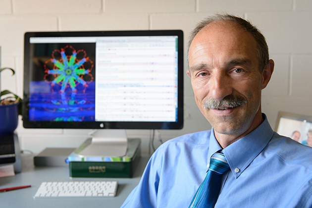 Peter Burkhard, professor of molecular and cell biology, with a computer image of the protein nanoparticle he designed. (Peter Morenus/UConn Photo)