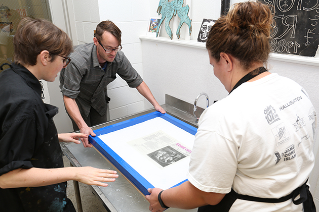 Artist-in-residence Louise Menzies, left, works in the print shop with John O'Donnell, assistant professor of printmaking, and a graduate student on one of her creations, embedding a newsletter into a piece of handmade paper for 'Time to Think Like a Mountain,' an exhibition at the Contemporary Art Galleries. (Linda Smith/UConn Photo)