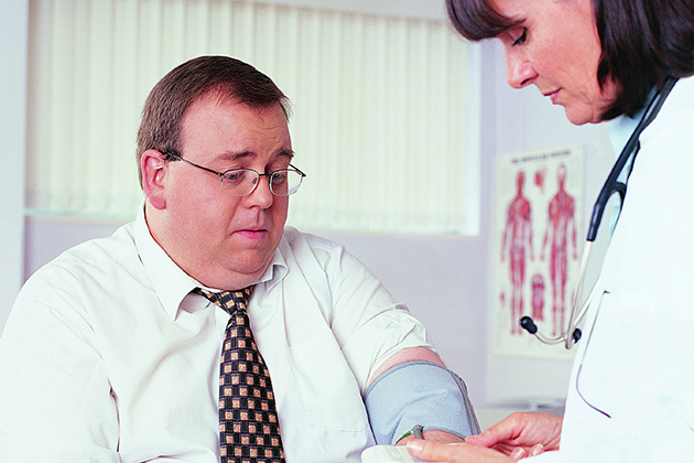 An overweight businessman has his blood pressure taken by a doctor. (Thinkstock/UConn Photo)