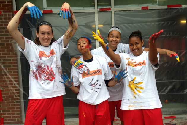 Members of the men's and women's 2014 NCAA Basketball Championship teams last summer created colorful abstract paintings by dipping basketballs in paint as part of the "In the Paint: Basketball in Contemporary Art" exhibit opening Jan. 23 at the William Benton Museum of Art on the UConn campus. From left: junior Breanna Stewart, sophomore Saniya Chong, and seniors Kiah Stokes and Kaleena Mosqueda-Lewis working on the canvas. (Kevin DeMille for UConn)