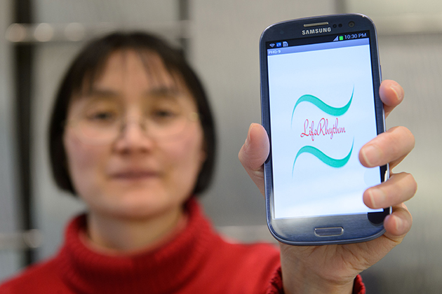 Bing Wang, associate professor of computer science and engineering, holds a smartphone with an application created to help monitor people with depression. (Peter Morenus/UConn Photo)