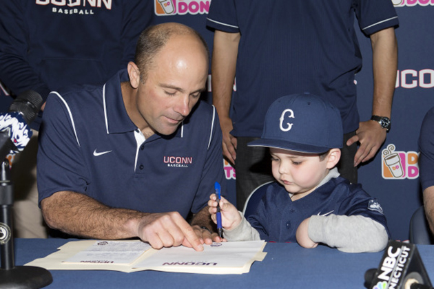 Baseball Head Coach Jim Penders shows five-year-old Grayson Hand where to sign his National Letter of Intent. (Stephen Slade '89 (SFA) for UConn)