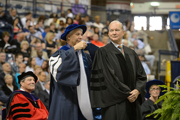 University Marshall Michael Darre hoods Philip Lodewick '66 (BUS), '67 MBA, as he receives an honorary degree at the School of Business commencement ceremony at Gampel Pavilion on May 11, 2014. (Peter Morenus/UConn File Photo)