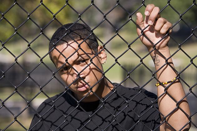A teen looks out from behind a fence. (iStock Photo)