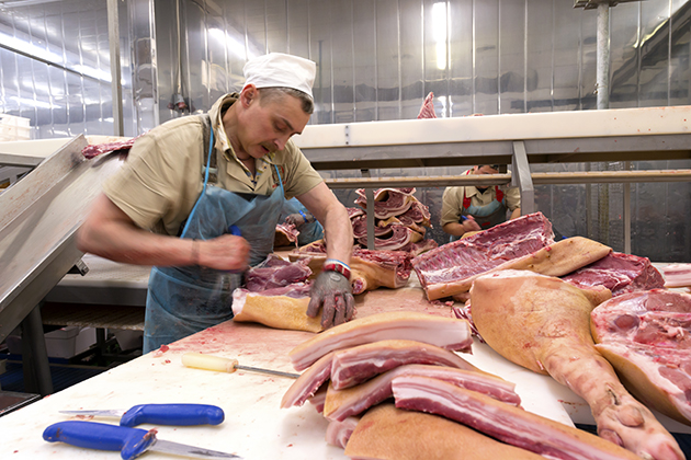 A butcher cutting meat at a pork processing plant. (iStock Photo)