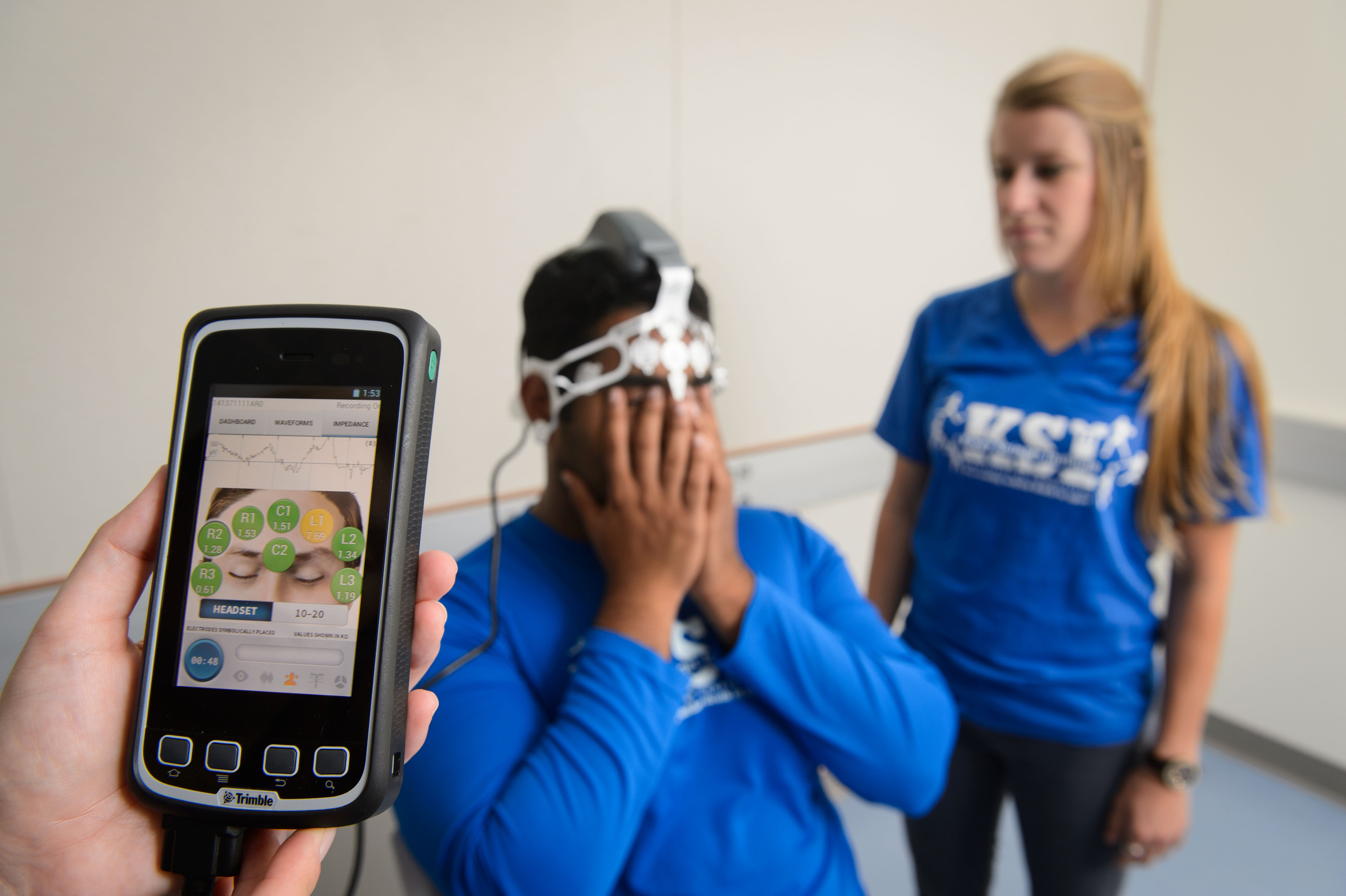 A device to evaluate concussions is demonstrated by Rohin Thomas '17 (CAHNR), left, and Sarah Attanasio '16 (CAHNR). (Peter Morenus/UConn Photo)