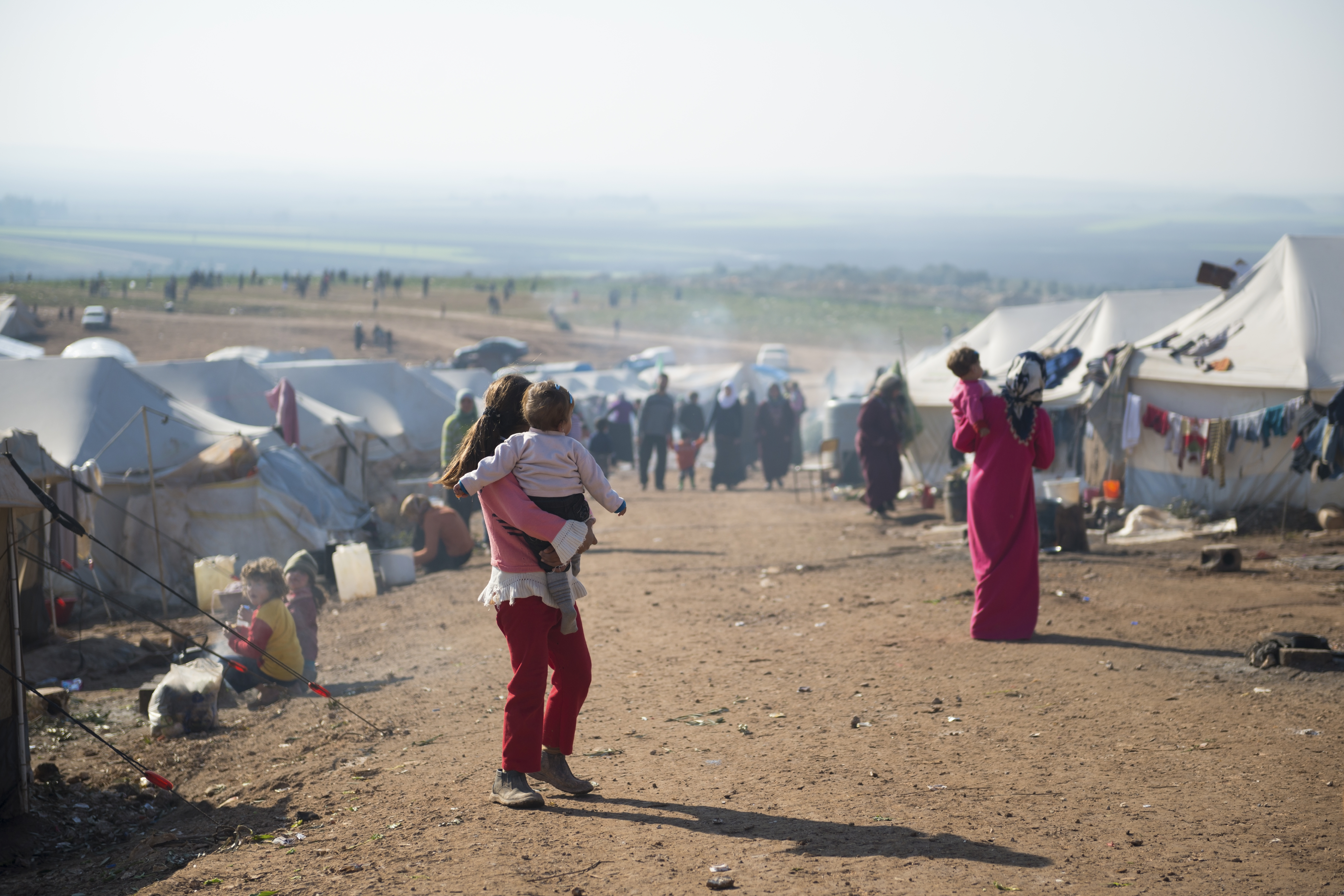 Syrian refugees walk outside their tents at a camp for internally displaced persons in Atmeh, Syria, adjacent to the Turkish border. (iStock Photo)