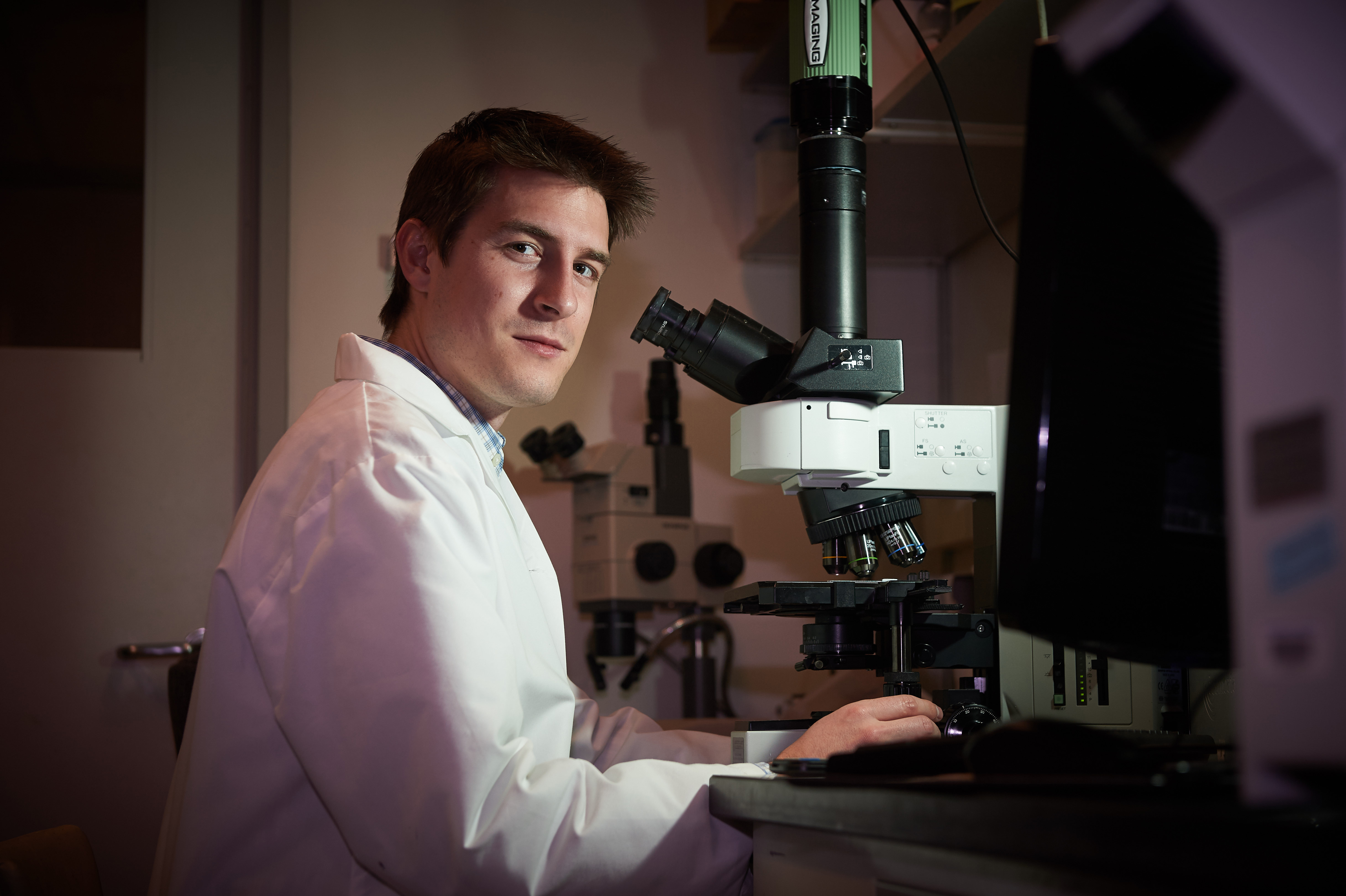 Matthew Hanley uses a microscope in a lab at UConn Health in Farmington on Dec. 3, 2015. (Peter Morenus/UConn Photo)