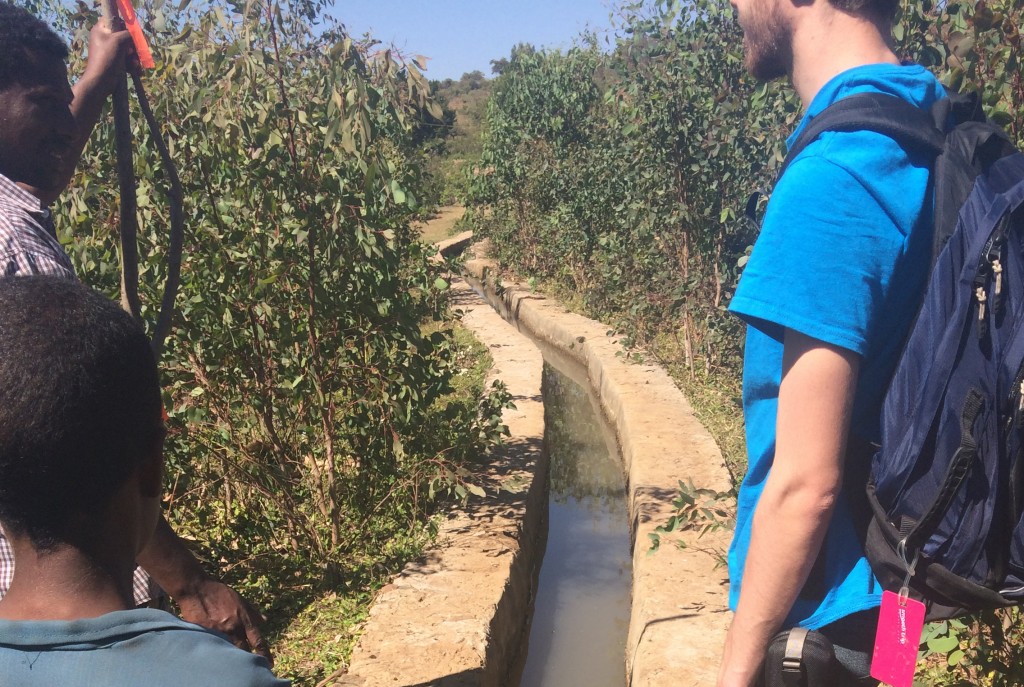 Ryan Cordier '18 (ENG), right, views the current irrigation system in an Ethiopian village along with two local residents.