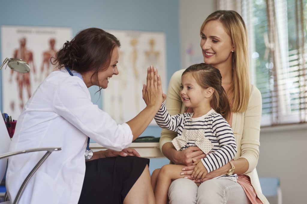 A doctor gives a child a high five for doing so well at her appointment. (iStock Photo)