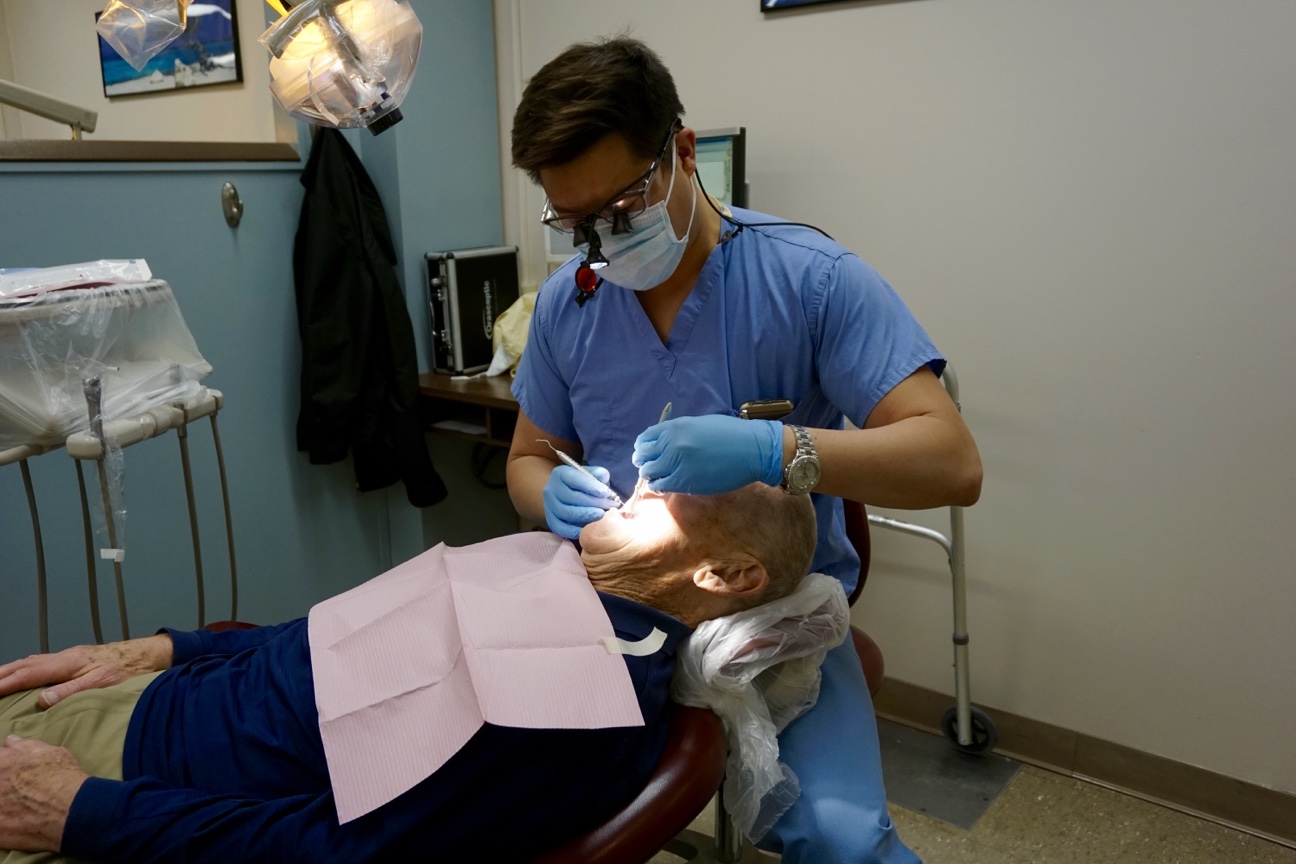 Jeffrey Pan examines a patient in the dental clinic. (Photo by Ze Horak)