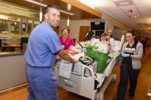 nursing staff moving a patient bed down a hospital hall
